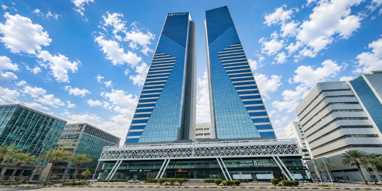 Twin skyscrapers with modern architecture against a blue sky with clouds.